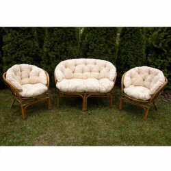 Komplet poduszek na rattanowy zestaw: 2 fotele i 1 sofa, do ogrodu. Kolor kremowy, bez wzoru, na tle zieleni.
