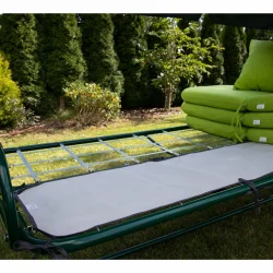 Podkład na siedzisko huśtawki ogrodowej, w jasnym kolorze, na całe siedzenie. Obok zielone poduszki ogrodowe.