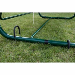 Stelaż do huśtawki ogrodowej na trawie, zielony. Kompletne mocowanie z widocznymi elementami stabilizacji.