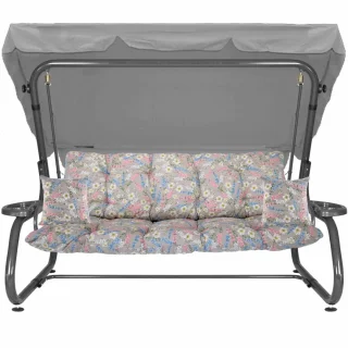 Huśtawka ogrodowa z szarym zadaszeniem, kolorowe poduszki w kwiaty, przeznaczona do ogrodu. Całość widoczna na zdjęciu.